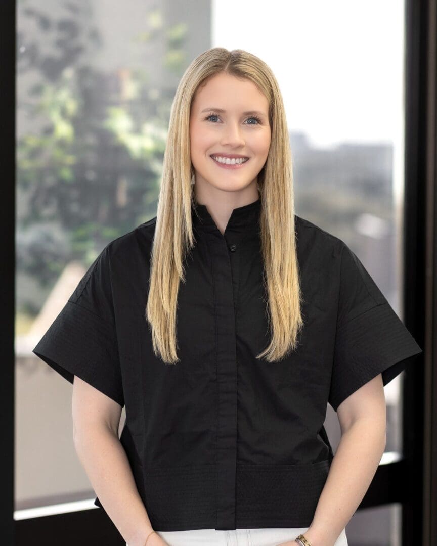 A woman in black shirt standing next to window.