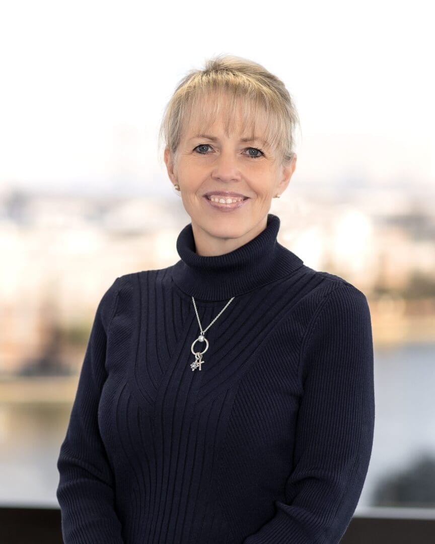 A woman in black sweater standing next to water.