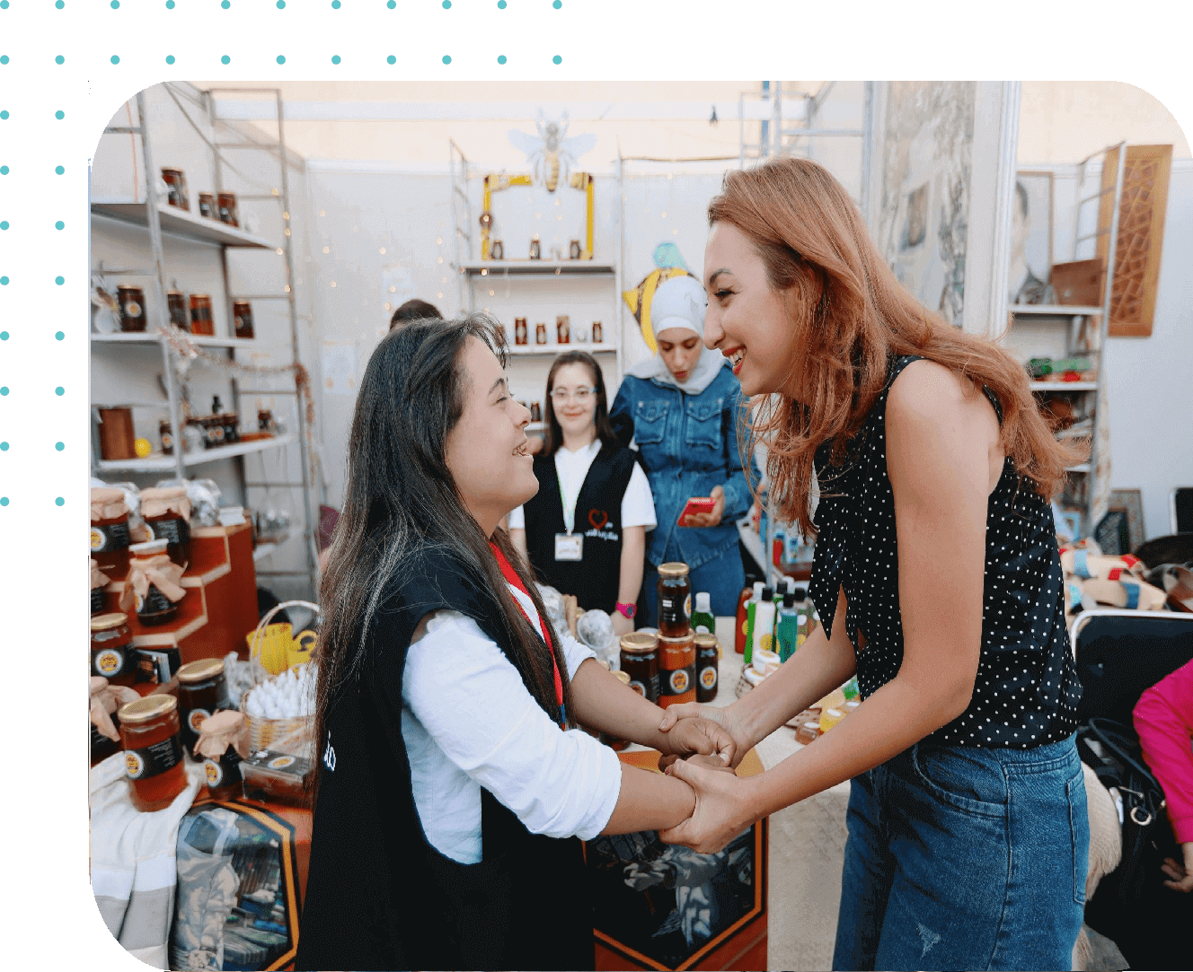 Two women smiling and shaking hands warmly.