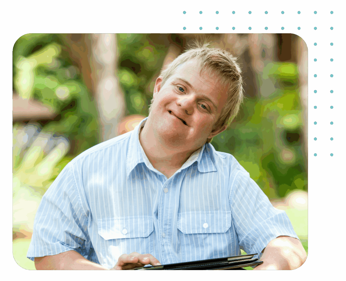 Man smiling outdoors, holding a tablet.